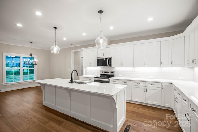 kitchen with a sink, stainless steel appliances, a kitchen island with sink, crown molding, and backsplash