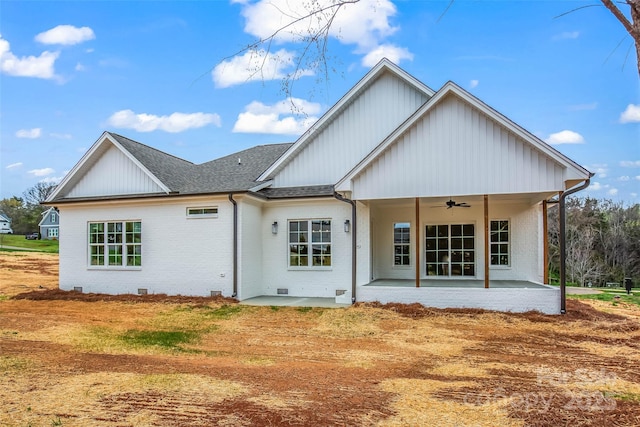 back of property with board and batten siding, a patio, brick siding, and ceiling fan