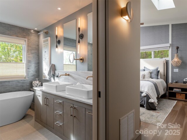 391 High Hickory Trl, Swannanoa, NC 28778 - full bathroom with ensuite bath, a freestanding bath, a skylight, double vanity, and wood finished floors