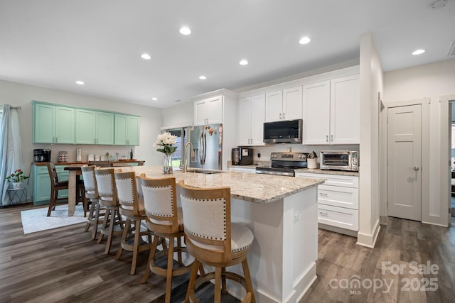 kitchen with a kitchen breakfast bar, dark wood-type flooring, a center island with sink, recessed lighting, and appliances with stainless steel finishes