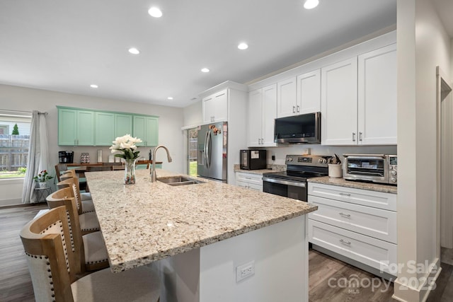 kitchen with a breakfast bar area, a toaster, dark wood finished floors, a sink, and appliances with stainless steel finishes