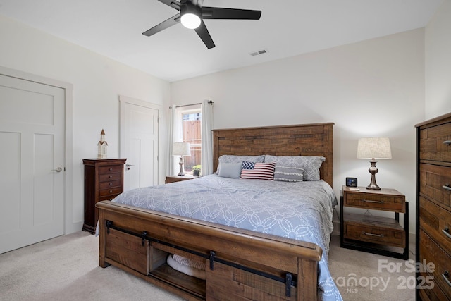 bedroom with visible vents, a ceiling fan, and light carpet