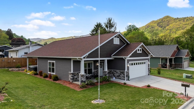 craftsman-style home featuring a front lawn, an attached garage, fence, and a mountain view