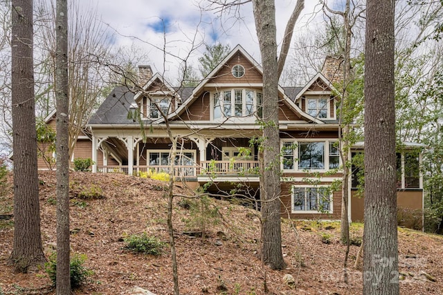 rear view of property with a chimney and a porch