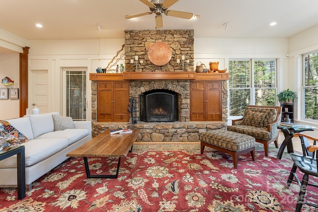 living area with a stone fireplace, ceiling fan, and recessed lighting