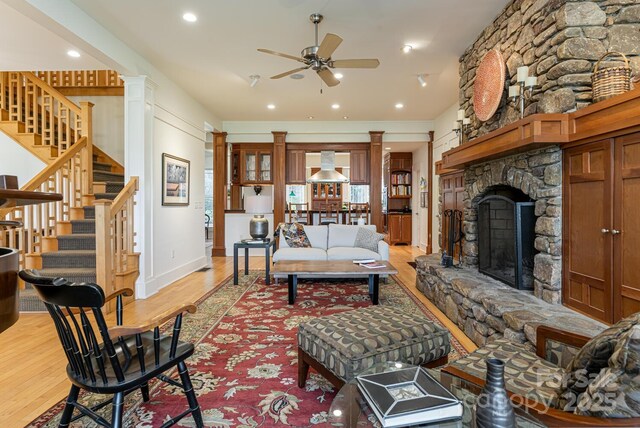 living area featuring a ceiling fan, light wood-type flooring, and decorative columns