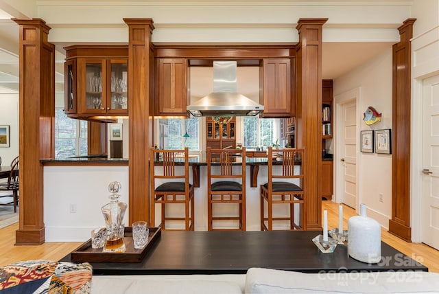 dining space featuring baseboards, light wood finished floors, and decorative columns