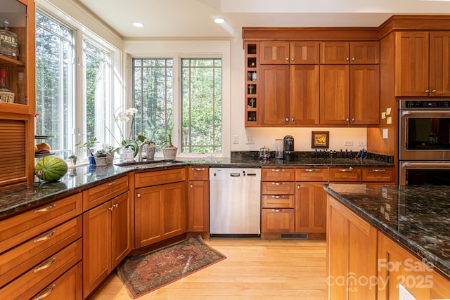 kitchen with dishwasher, stainless steel double oven, brown cabinets, and a sink