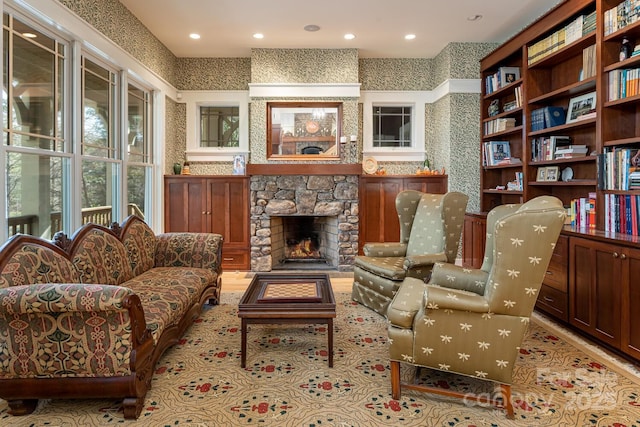 living area featuring a stone fireplace and recessed lighting