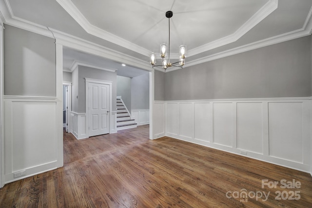 5633 Open Book Ln, Charlotte, NC 28270 - unfurnished dining area with a tray ceiling, a decorative wall, a chandelier, wood finished floors, and stairway