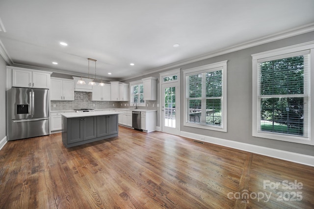 5633 Open Book Ln, Charlotte, NC 28270 - kitchen featuring appliances with stainless steel finishes, crown molding, light countertops, white cabinets, and backsplash