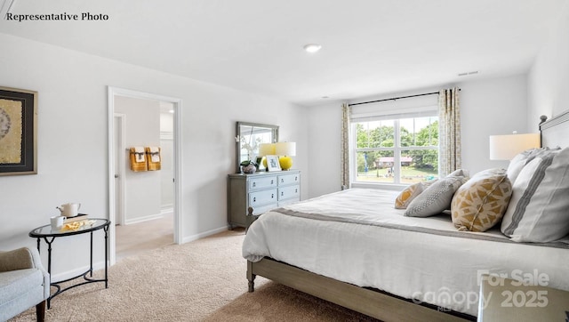 bedroom featuring ensuite bath, light colored carpet, baseboards, and visible vents