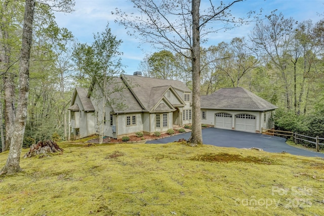 view of front facade featuring asphalt driveway, an attached garage, and a chimney