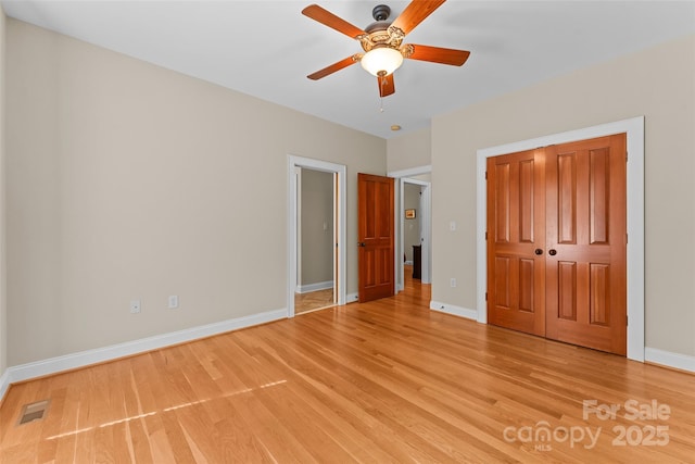 unfurnished bedroom featuring light wood finished floors, baseboards, a closet, and a ceiling fan