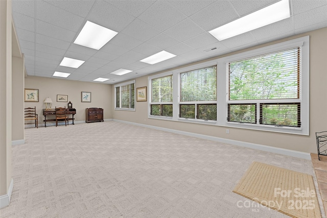 interior space featuring carpet flooring, a drop ceiling, and baseboards