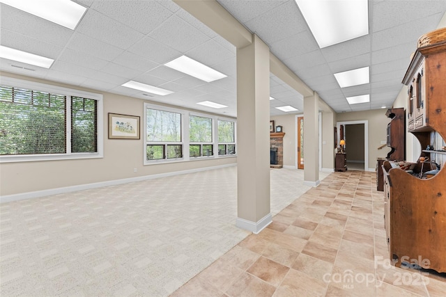 interior space featuring a paneled ceiling, light carpet, baseboards, and a fireplace