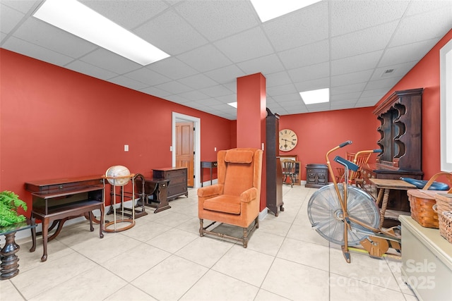 sitting room with a drop ceiling, a wood stove, and tile patterned floors