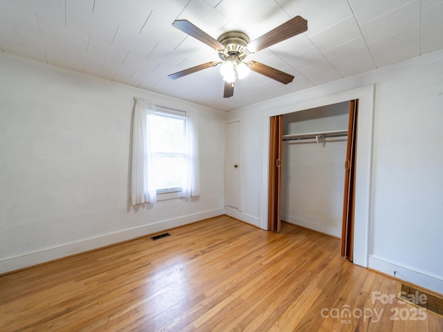unfurnished bedroom featuring ornamental molding, a closet, light wood-style flooring, and visible vents