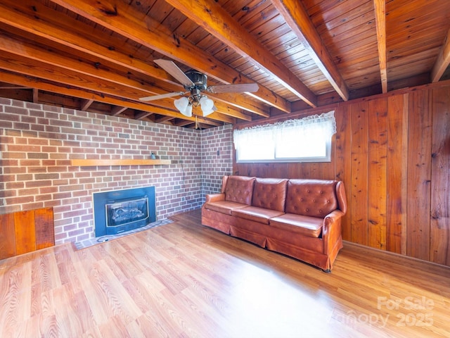 living area with ceiling fan, beam ceiling, wooden walls, and wood finished floors