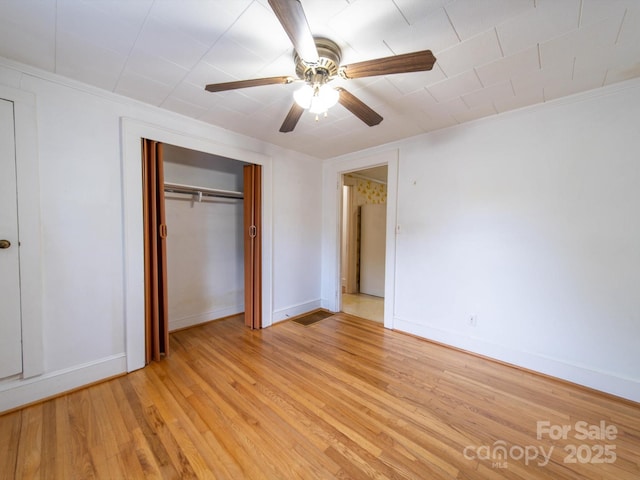 unfurnished bedroom with light wood-style flooring, a closet, baseboards, ceiling fan, and ornamental molding