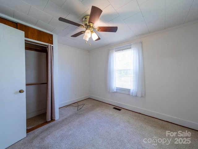 unfurnished bedroom with a closet, carpet, visible vents, ceiling fan, and baseboards