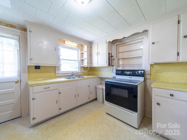 kitchen with backsplash, light countertops, a sink, and range with electric cooktop