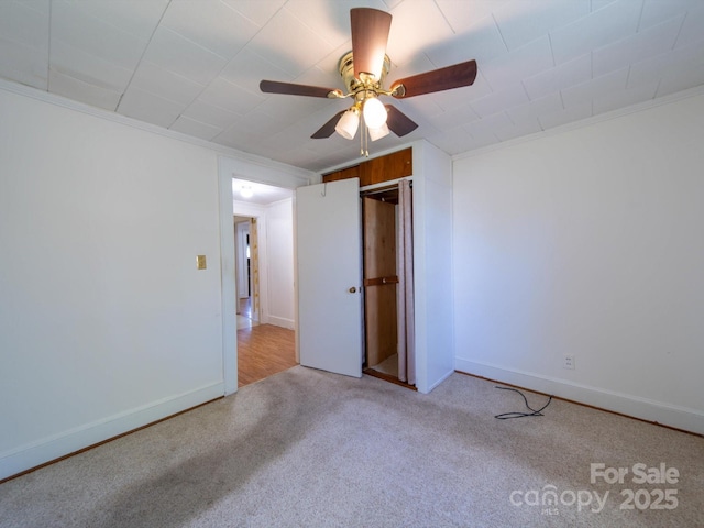 interior space featuring crown molding, baseboards, ceiling fan, and carpet floors