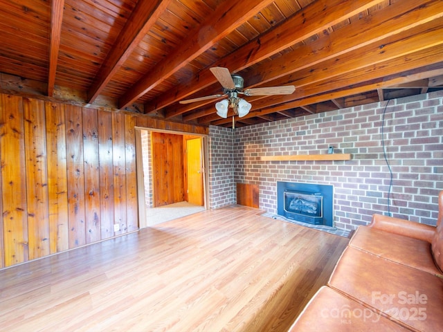 unfurnished living room featuring wood finished floors, beam ceiling, wooden ceiling, ceiling fan, and a fireplace with flush hearth