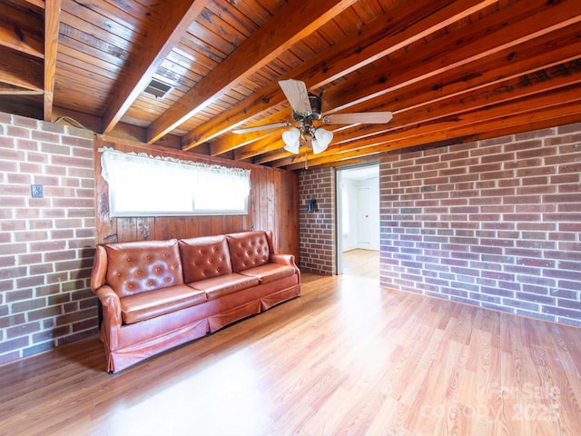 living room with a ceiling fan, brick wall, beam ceiling, and wood finished floors