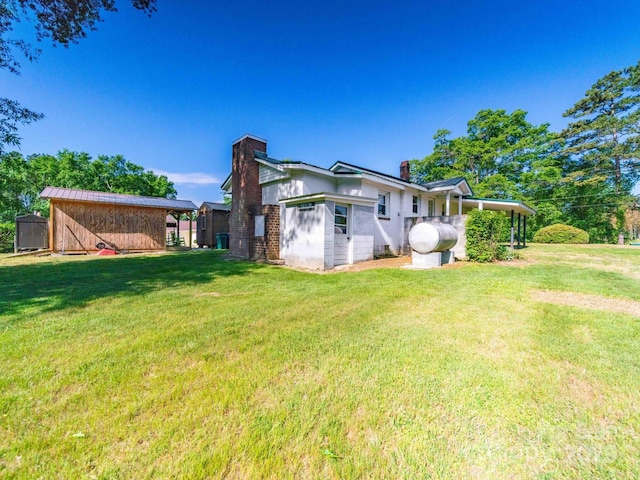 rear view of property featuring a yard, heating fuel, and a chimney