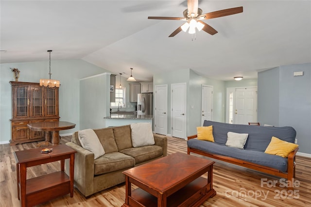 living room featuring light wood-type flooring, vaulted ceiling, a ceiling fan, and a chandelier