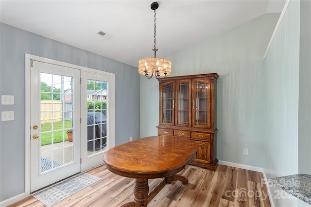 dining room featuring light wood-type flooring, a chandelier, and baseboards