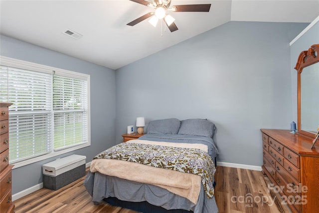 bedroom with wood finished floors, vaulted ceiling, baseboards, and ceiling fan