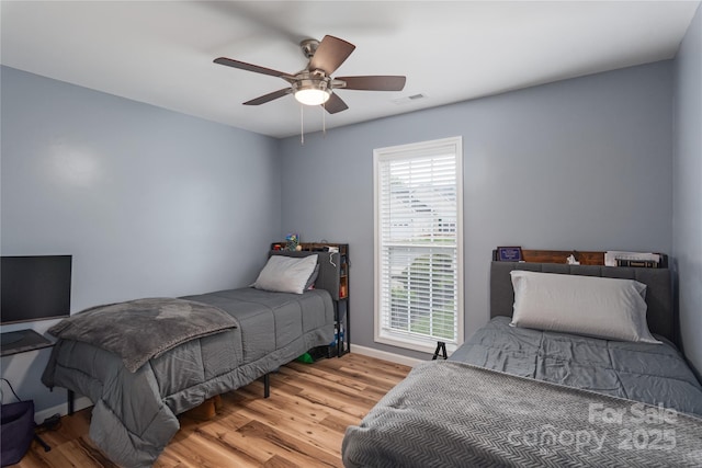 bedroom featuring wood finished floors, baseboards, and a ceiling fan
