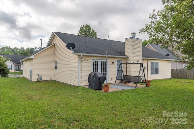 back of house featuring a patio, a chimney, and a shingled roof
