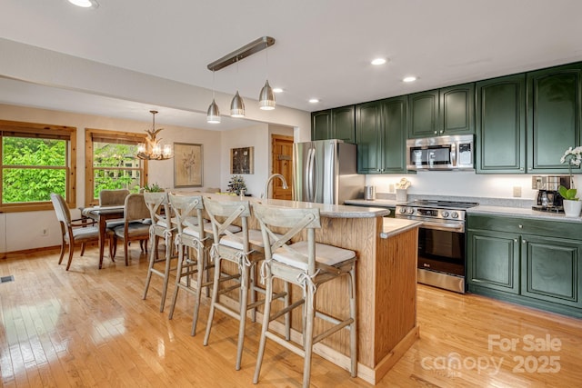 61 Ivy Ridge Rd, Burnsville, NC 28714 - kitchen with green cabinets, appliances with stainless steel finishes, light wood-style floors, a chandelier, and a breakfast bar