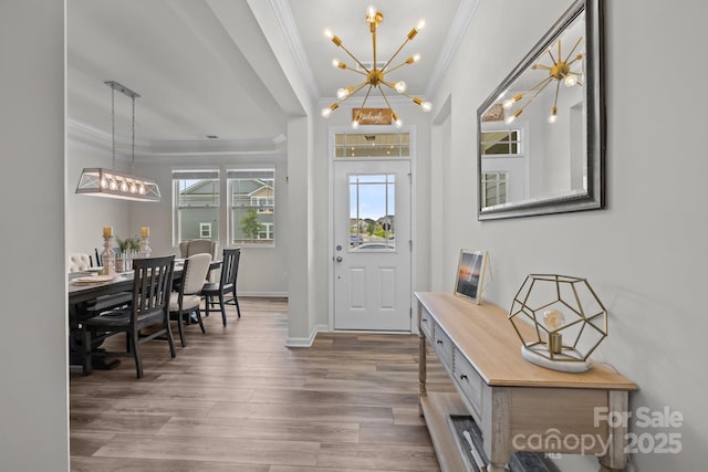 entryway with crown molding, a chandelier, wood finished floors, and baseboards
