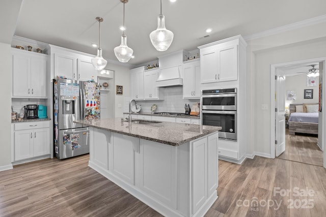 kitchen featuring a sink, appliances with stainless steel finishes, backsplash, ornamental molding, and white cabinetry
