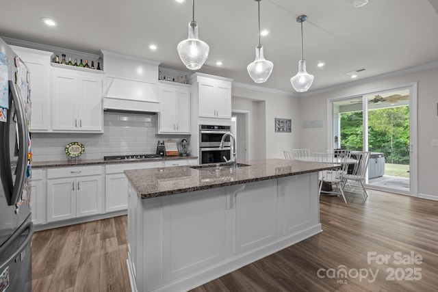 kitchen featuring stainless steel appliances, crown molding, wood finished floors, a sink, and tasteful backsplash