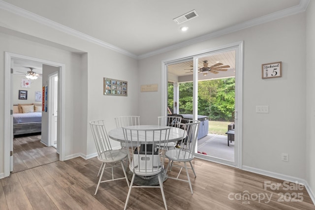 dining room with wood finished floors, baseboards, crown molding, and a ceiling fan