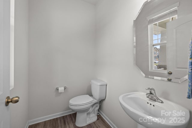 bathroom with a sink, wood finished floors, toilet, and baseboards