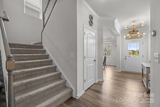 entrance foyer featuring stairs, a chandelier, crown molding, wood finished floors, and baseboards