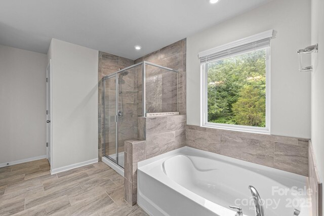 full bath with a stall shower, a garden tub, recessed lighting, and baseboards
