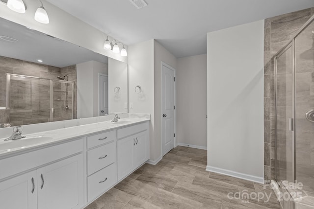 full bathroom featuring a stall shower, double vanity, and baseboards