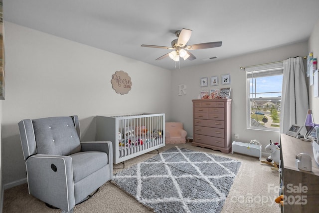 bedroom with carpet floors, a nursery area, baseboards, and ceiling fan