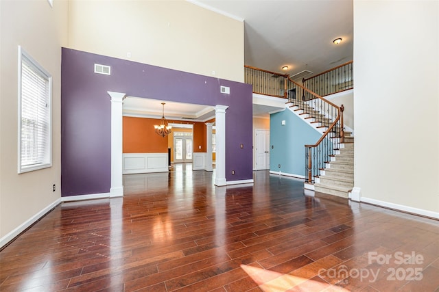 4504 Rockland Ct, High Point, NC 27265 - unfurnished living room featuring decorative columns, a high ceiling, a chandelier, crown molding, and wood finished floors