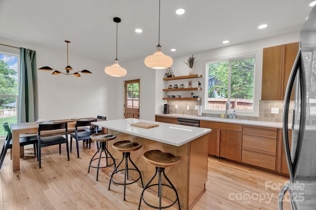 30 Spaulding Dr, Candler, NC 28715 - kitchen featuring freestanding refrigerator, brown cabinetry, a sink, a kitchen island, and decorative backsplash