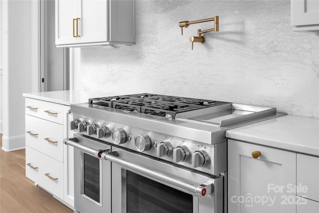 details featuring white cabinetry, double oven range, and light wood finished floors