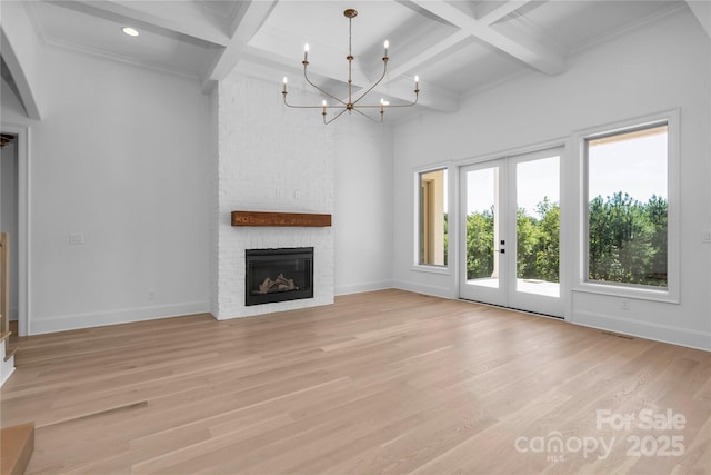 unfurnished living room with light wood finished floors, coffered ceiling, beam ceiling, and french doors