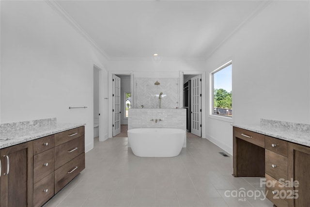 bathroom featuring a freestanding bath, baseboards, vanity, and ornamental molding